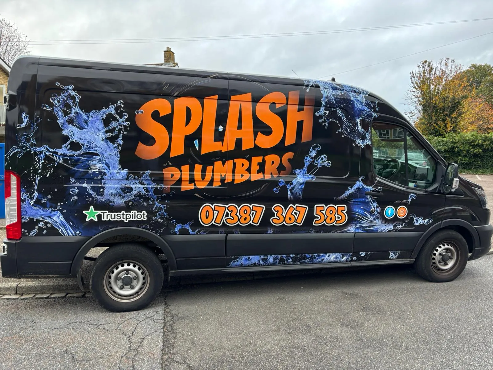 Black van with blue water splash graphics and orange text reading 'Splash Plumbers' and a phone number.